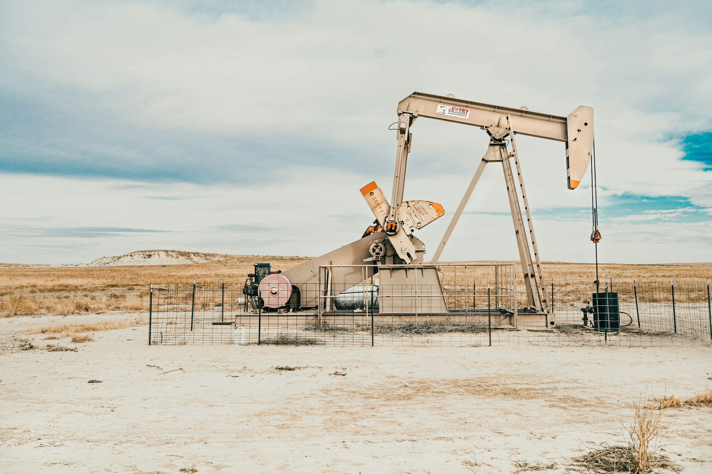 A pump jack on open prairie under a wide western sky